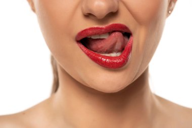 Dili beyaz arka planda dudaklarına dokunan bir kadının yakın plan fotoğrafı.