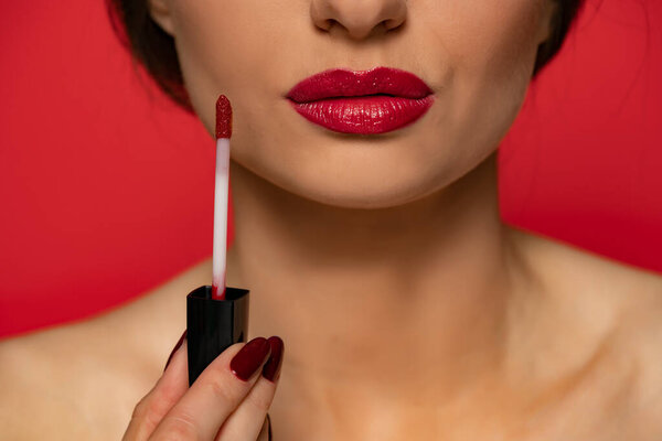 a woman advertises a red lip gloss on red background