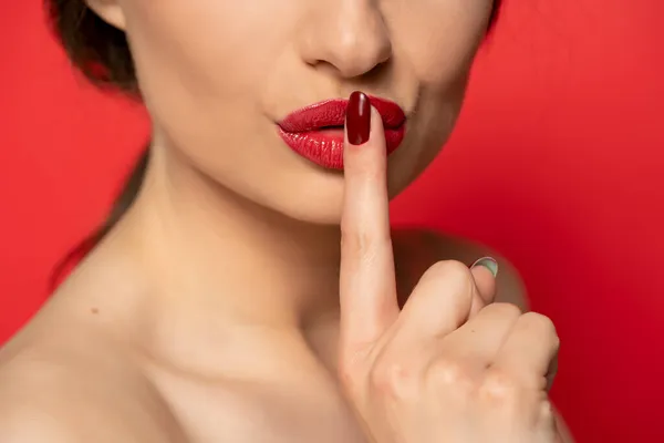 赤い唇の前に指がある女性の近くに赤い背景があります 黙示録 — ストック写真