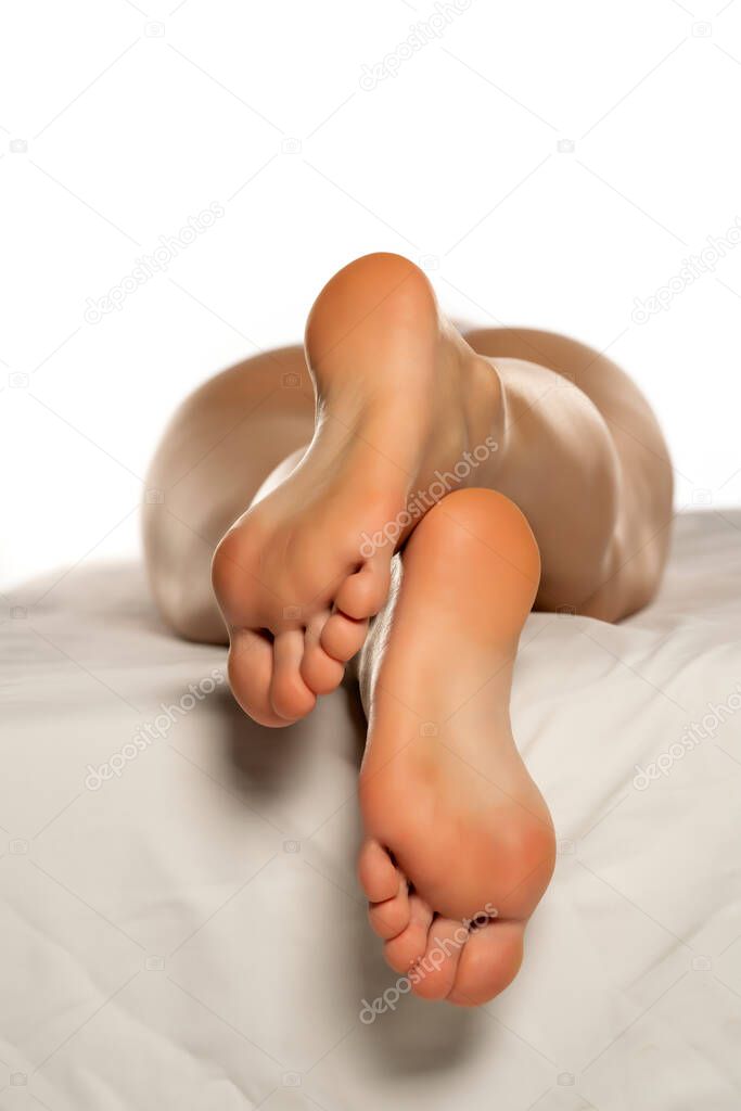 female crossed soles on a white bed and white background