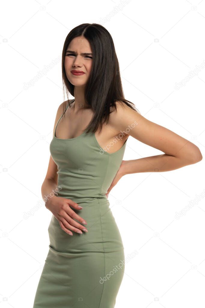 Backache. Young woman suffering from back pain on a white background