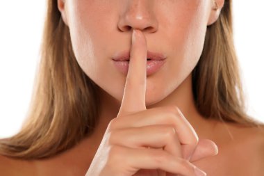 Beyaz arka planda dudaklarında parmak olan bir kadın. Sessizlik kavramı