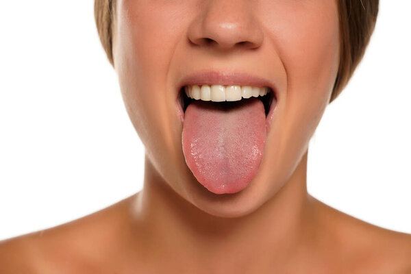 young woman sticking out her tongue on white background