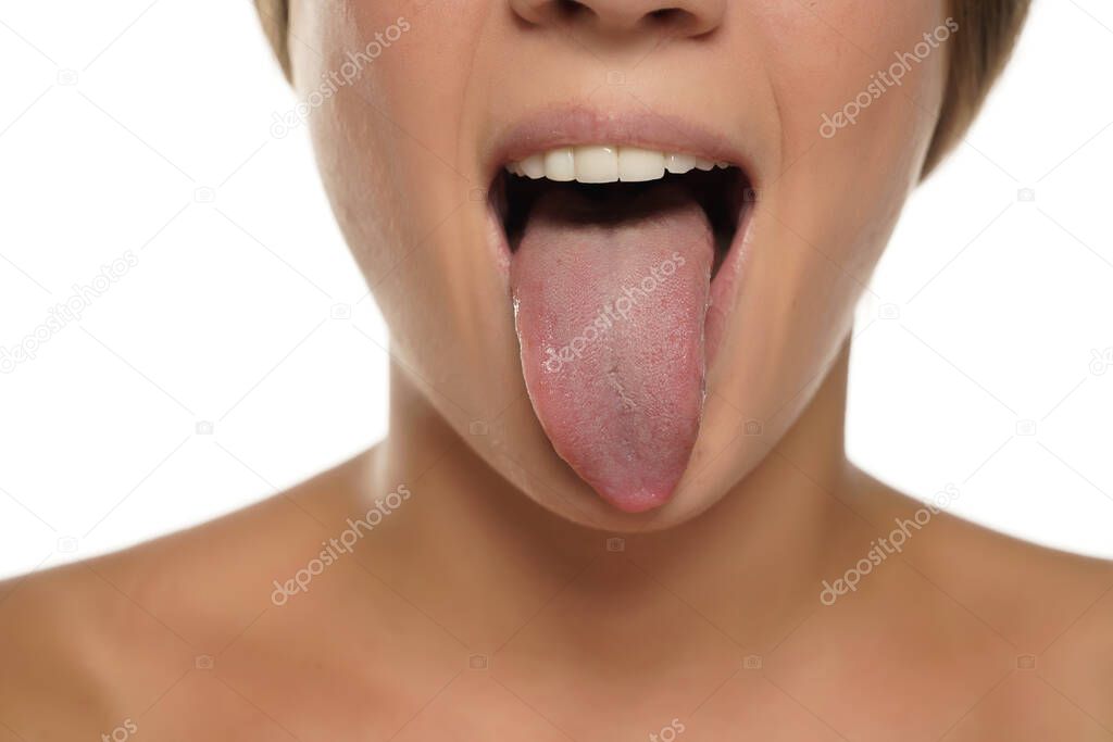 young woman sticking out her tongue on white background