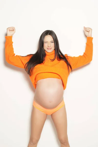 白い背景にオレンジのセーターを着た妊婦が — ストック写真