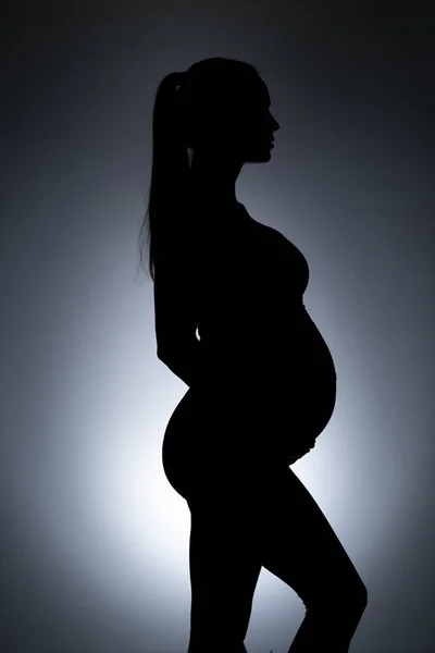 Gri Arka Planda Hamile Bir Kadının Silüeti — Stok fotoğraf
