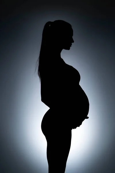 Silhouet Van Een Jonge Zwangere Vrouw Een Grijze Achtergrond — Stockfoto