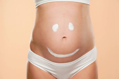 Müstakbel annenin karnı, üzerine gülen surat çizilmiş bej bir arka plan.