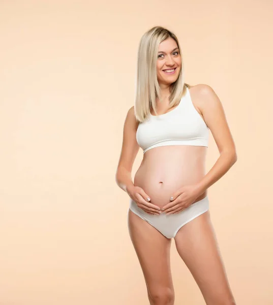 Çamaşırlı Hamile Kadın Bej Arka Planda Poz Veriyor — Stok fotoğraf