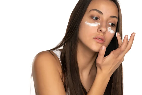 Uma Jovem Mulher Bonita Aplica Creme Facial Fundo Branco — Fotografia de Stock