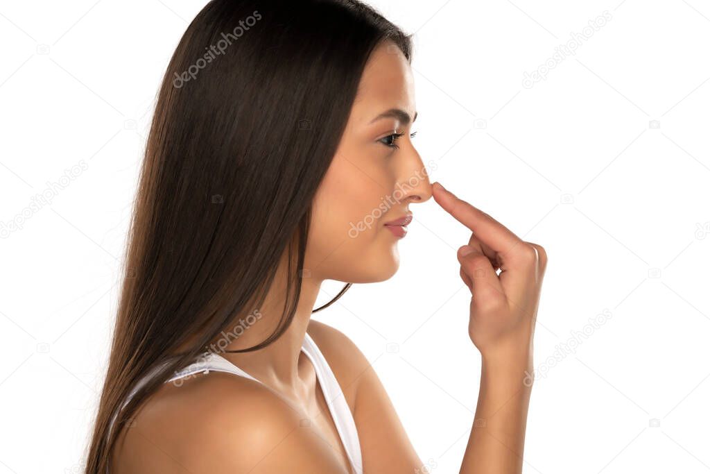 profile of a young smiling woman touching her nose on a white background