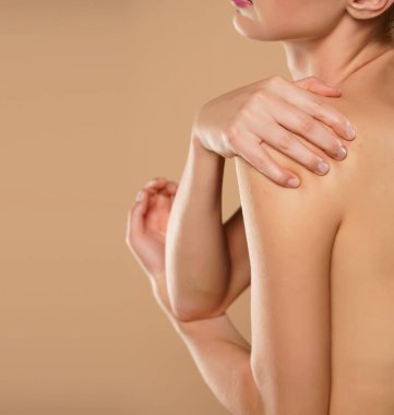 Bej arka planda omuz ağrısı olan bir kadın.