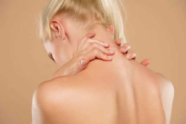 Woman with neck pain on a beige background