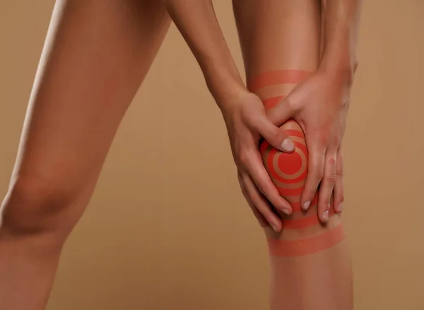 Vrouw Houden Haar Pijn Knie Een Beige Achtergrond — Stockfoto