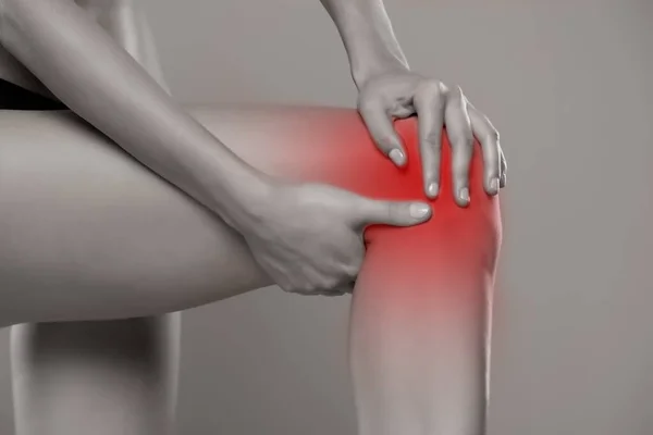 Mujer Sostiene Rodilla Dolorida Sobre Fondo Gris — Foto de Stock