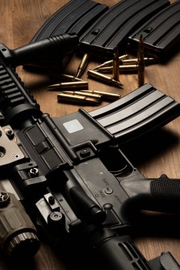 Optik görüşlü m4 tüfek, mühimmat ve mermiler ahşap masada.