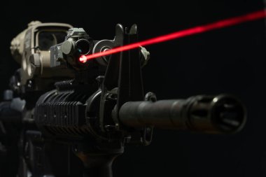 Optik görüş ve lazer cihazı. Arka planda M4 tüfeği üzerinde kırmızı bir ışın var.