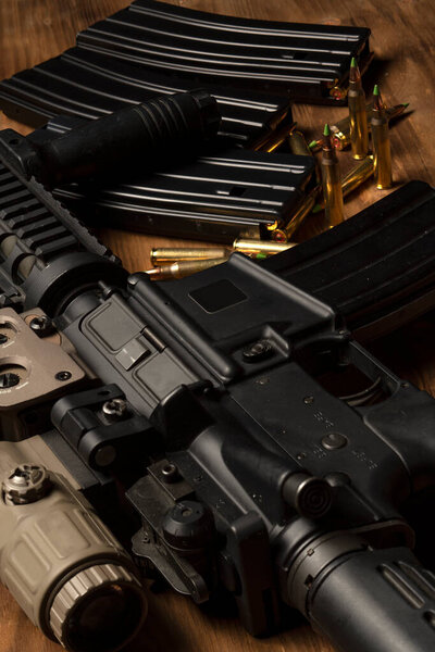 m4 rifle with optical sight, ammunition and cartriges on wooden table