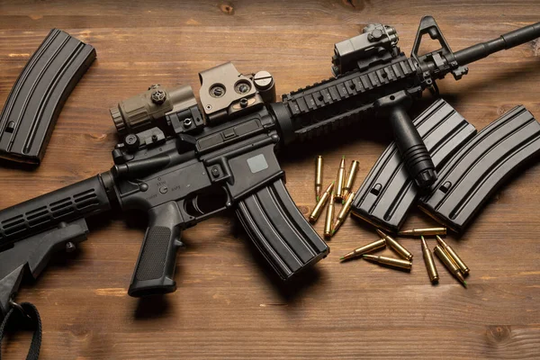 Optik görüşlü m4 tüfek, mühimmat ve mermiler ahşap masada.