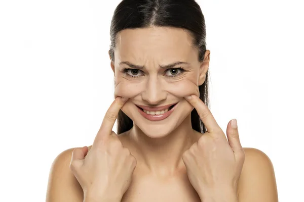 Jovem Mulher Nervosa Forçando Seu Sorriso Com Dedos Fundo Branco — Fotografia de Stock