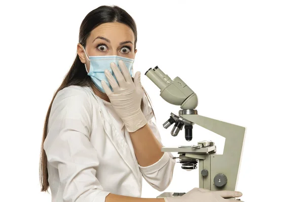 Portret Van Geschokte Vrouwelijke Wetenschapper Met Microscoop Een Witte Achtergrond — Stockfoto