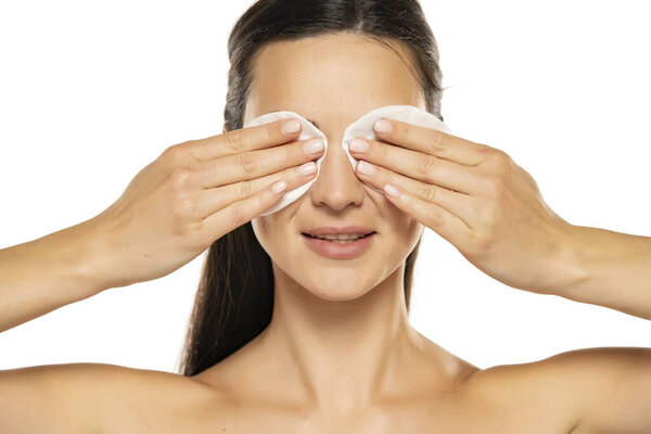 Healthy fresh woman removing makeup from her face with cotton pads.  Isolated on isolated white background. Skin care and beauty concept.