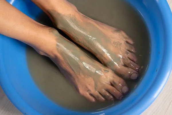 a woman\'s foot in a blue washbowl of water