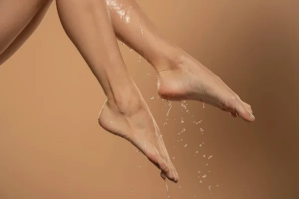 在米色背景下 一只雌性湿腿和脚与水滑过它们的近距离接触 — 图库照片