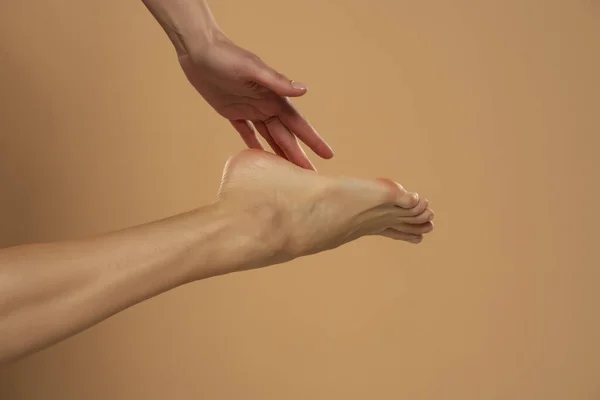 脚后跟护肤 妇女用手触摸健康的脚体 腿脱离米色背景 — 图库照片