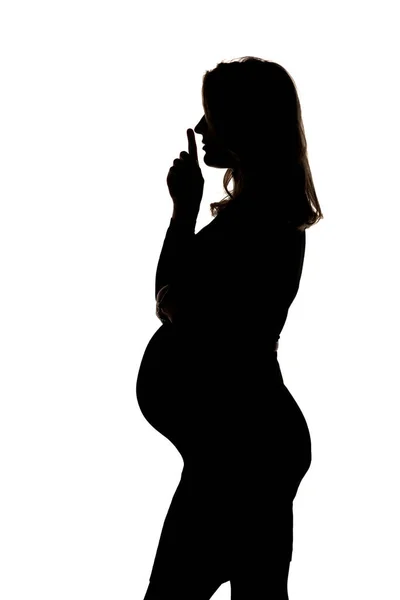 Silhouette Una Donna Incinta Con Dito Sulle Labbra Posa Studio — Foto Stock