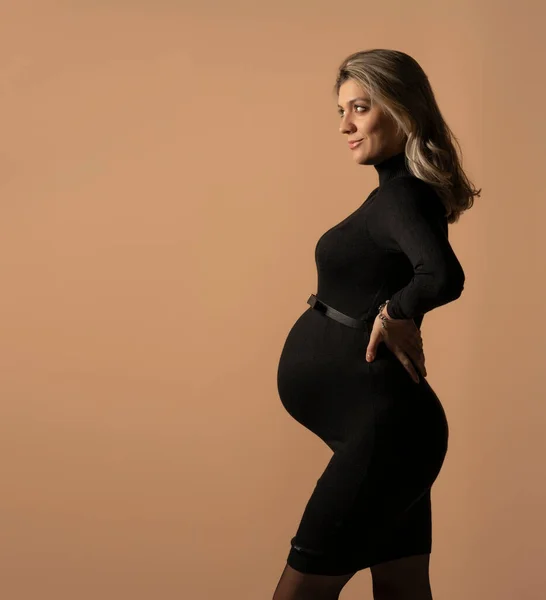Těhotná Žena Těsné Černé Šaty Pózovat Studiu Béžovém Pozadí — Stock fotografie