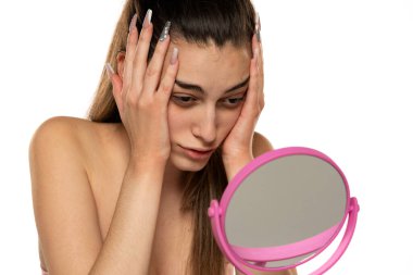 Can sıkıntısı içindeki genç bir kadın beyaz bir arka planda başını aynanın önüne yasladı.