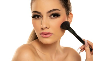 Beyaz arka plana allık süren güzel bir genç kadının portresi.