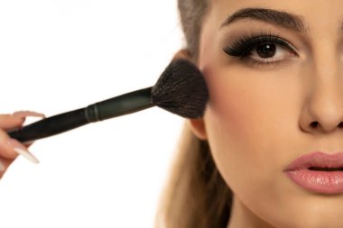 Beyaz arka plana allık süren güzel genç bir kadının yarım portresi.