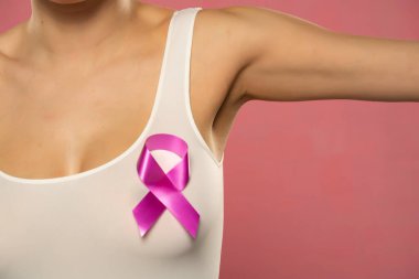 Kanserli, pembe arka planda farkındalık kurdelesi olan gömlekli genç bayanı kapat.