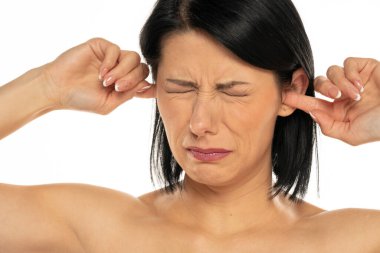 Beyaz arka planda parmaklarını kulaklara koyarken bağıran rahatsız genç bir kadının portresi