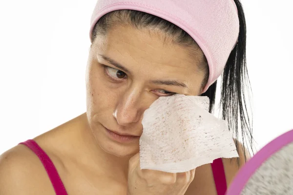 中年妇女在白色背景上用湿巾擦拭自己的脸 — 图库照片