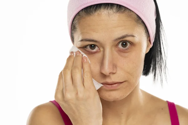 中年妇女在白色背景上用湿巾擦拭自己的脸 — 图库照片