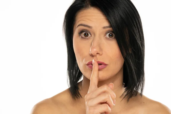 一个中年妇女的画像 手指在嘴唇前面 背景为白色 — 图库照片