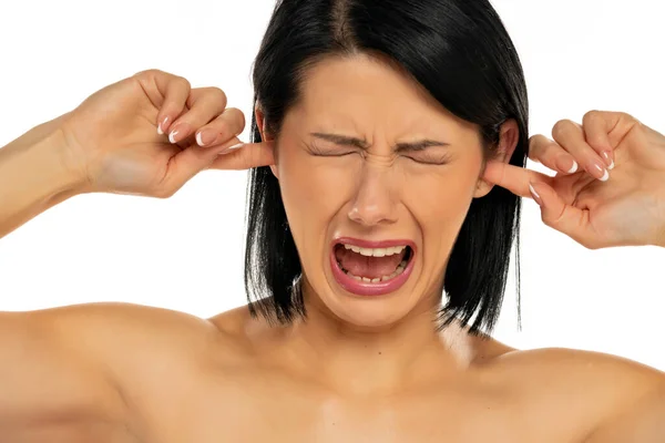 Portrait Disturbed Young Woman Shouting While Putting Fingers Ears White — стоковое фото