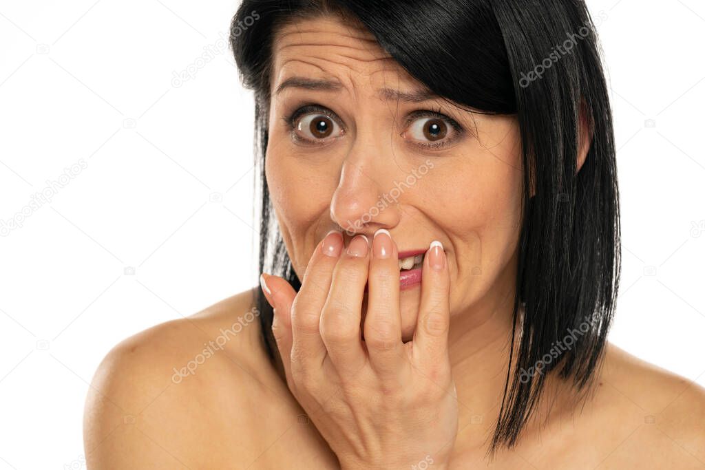 Young woman holding her hands in front of her mouth in shame on white background