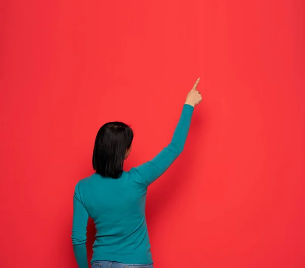 Kırmızı Duvardaki Bir Şeyi Gösteren Bir Kadının Arka Görüntüsü — Stok fotoğraf