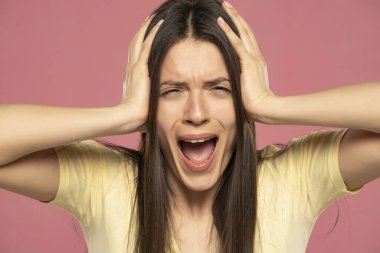 Kapanış portresi. Pembe arka planda öfke nöbeti geçiren sinirli bir kadın bağırıyor. Negatif insani duygu yüz ifadesi tepkisi