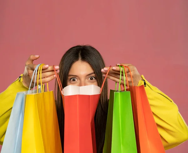 Young Happy Woman Peeking Her Shopping Bags Pink Background — стоковое фото