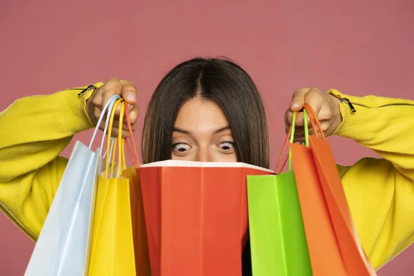 Young Happy Woman Peeking Her Shopping Bags Pink Background — Fotografia de Stock