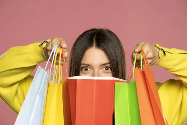 Young Happy Woman Peeking Her Shopping Bags Pink Background — стоковое фото