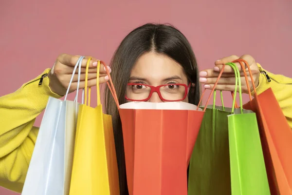 Young Happy Woman Red Eyeglasses Peeking Her Shopping Bags Pink — Fotografia de Stock