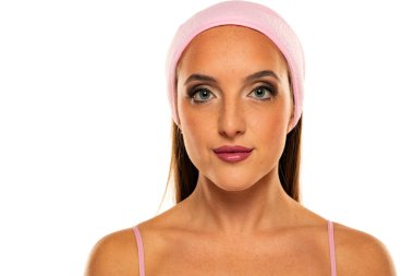 Beyaz bir arka planda makyaj ve saç bandı olan güzel bir kadının portresi.