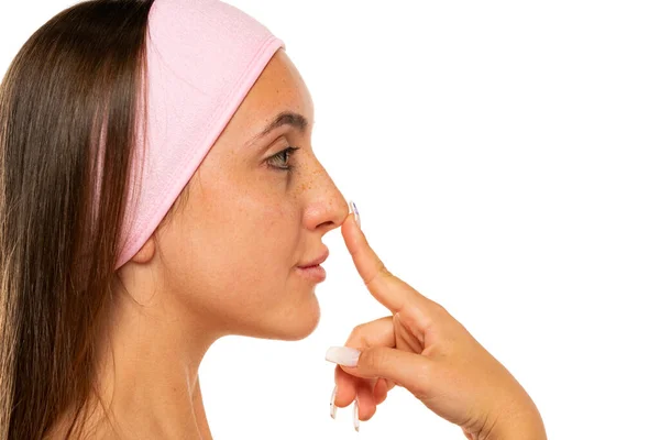 一个没有化妆的年轻雀斑女人在白色背景下触摸鼻子的轮廓 — 图库照片