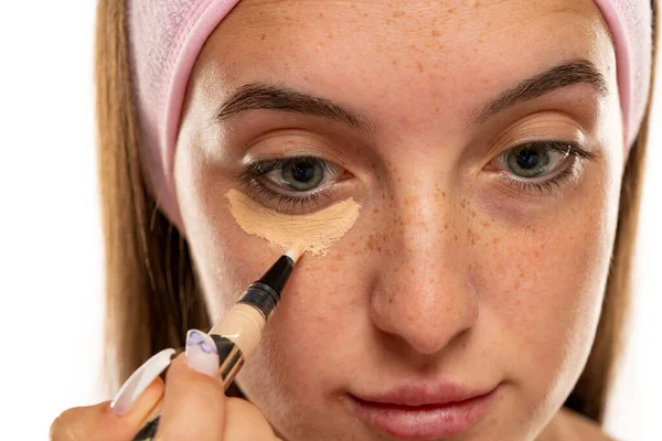 Young Freckles Woman Applyes Concealer Her Eyes White Background — Stok Foto
